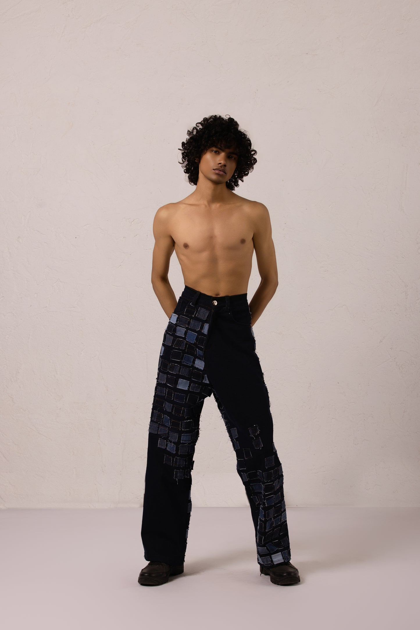 Model wearing baggy denim with sewn patches in a bold diagonal pattern, crafted from Denim Lycra.