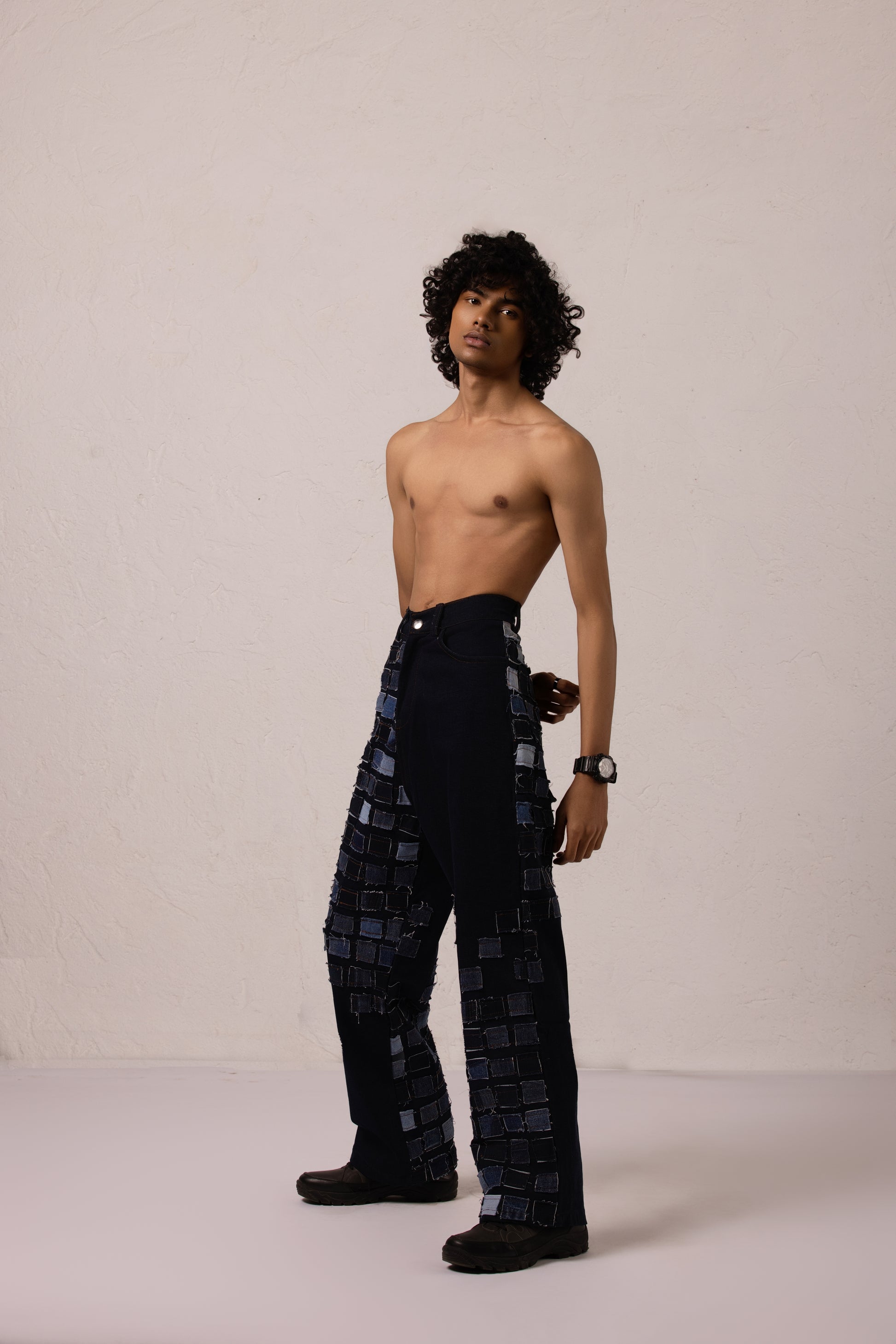 Model wearing baggy denim with sewn patches in a bold diagonal pattern, crafted from Denim Lycra.