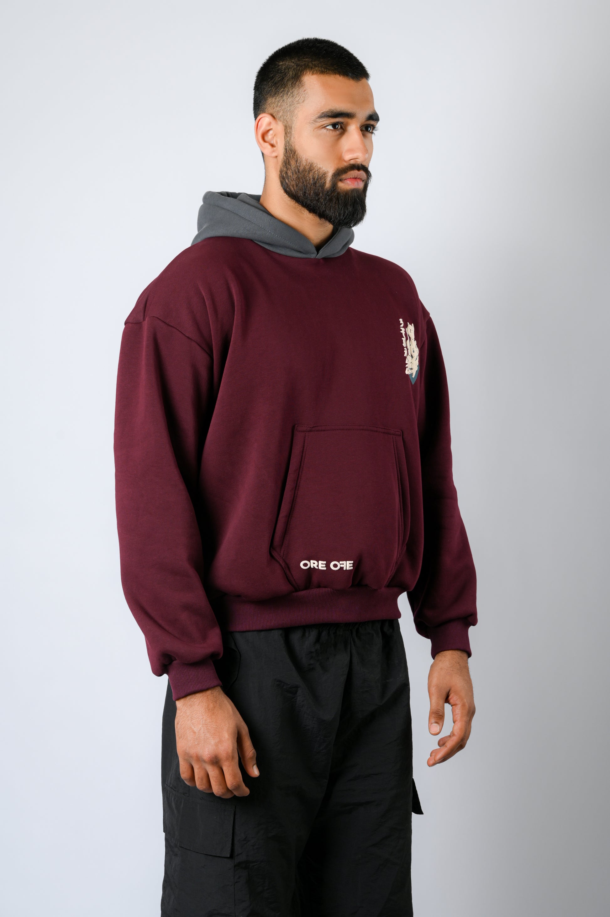 maroon hoodie with a contrasting dark grey hood features a cat strumming the shamisen