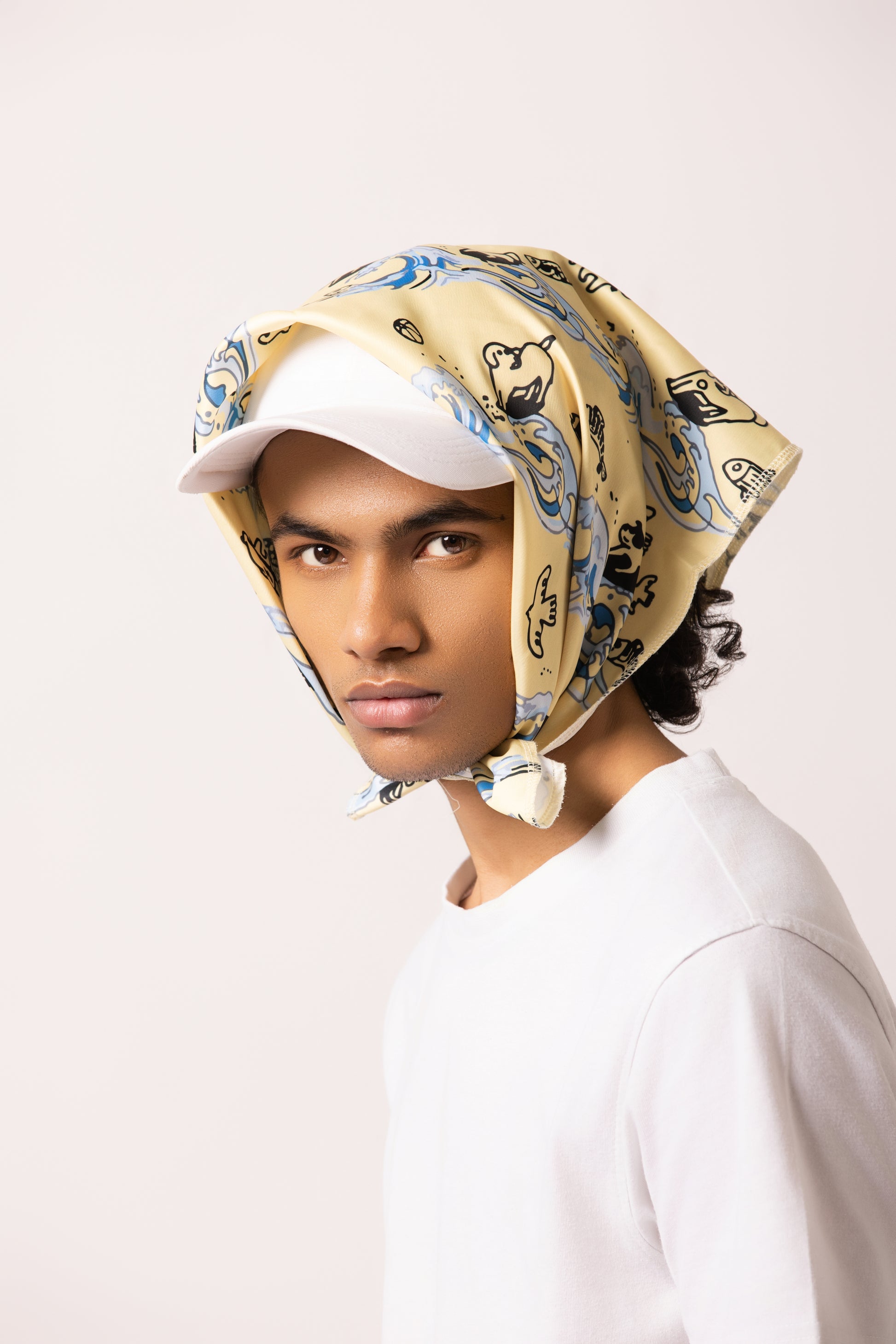 Model wearing the Surf Up Multi-purpose Bandana as a headband, featuring a surfing dog design, made from 100% cotton."