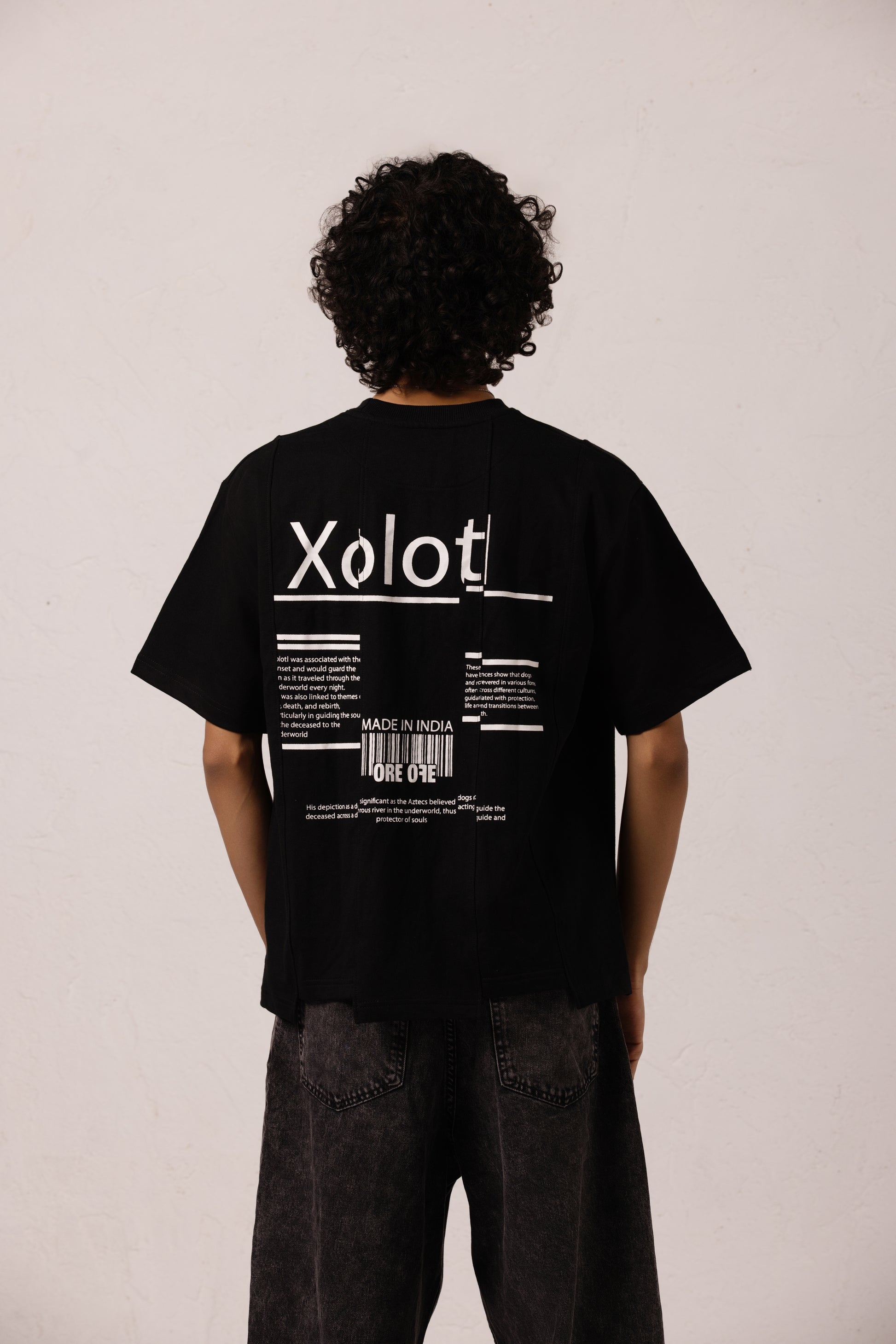 Model wearing Xolotl black Oversized T-shirt with Aztec dog god design, 100% Terry Cotton, embroidery & screen printing. Showing back